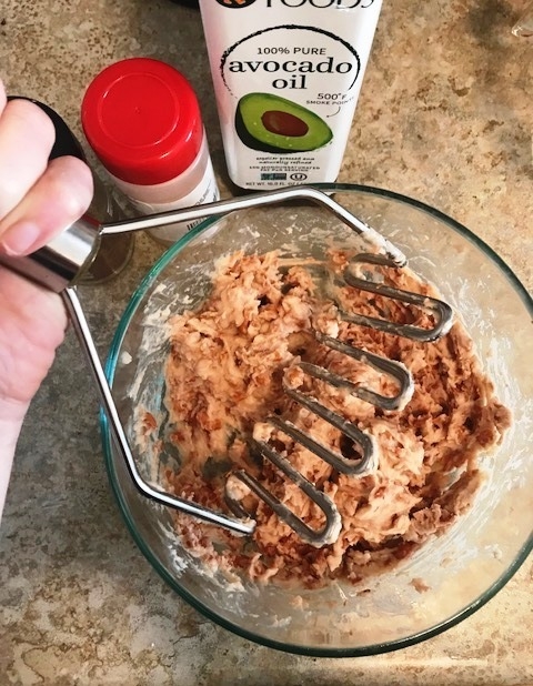 Mashing healthy refried pinto beans with avocado oil