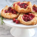 Cranberry brie cheese puff pastry on white cakestand and white marble background