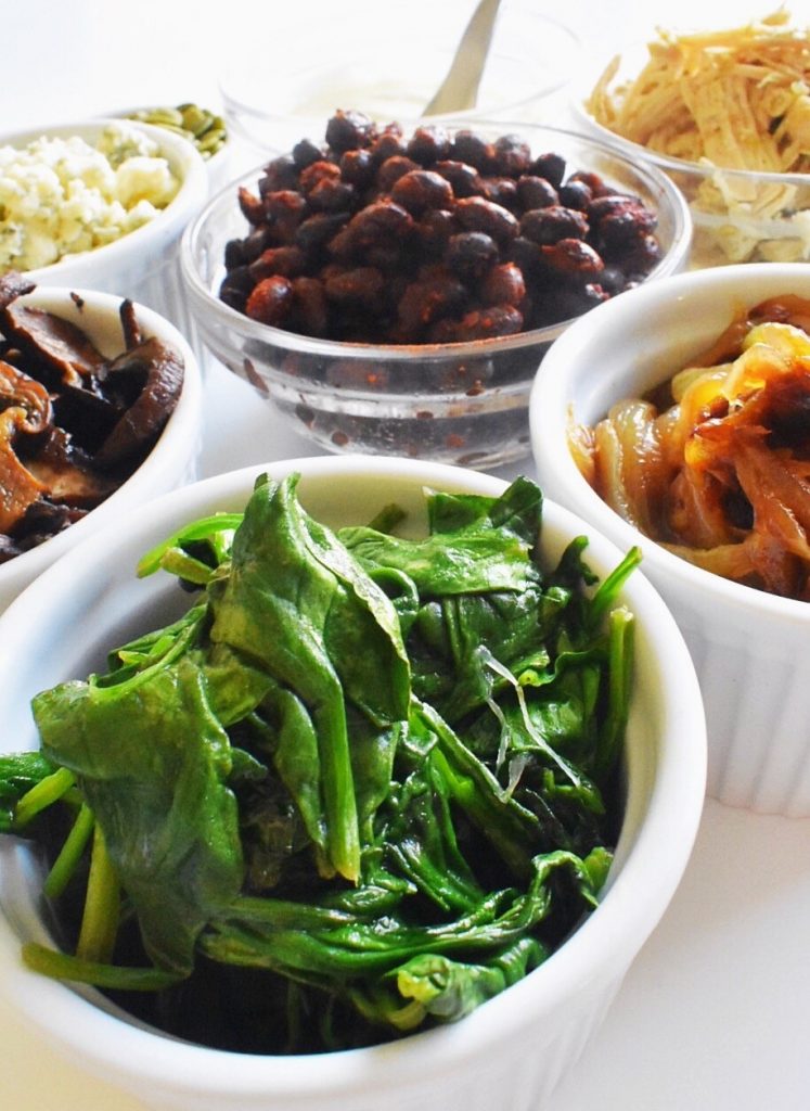 loaded baked potato bar sauteed spinach black beans sauteed mushrooms and caramelized onions in white ramekins