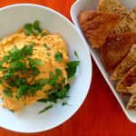 red lentil hummus with pita chips on orange place mat