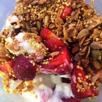 bowl of plain yogurt topped with granola and strawberries