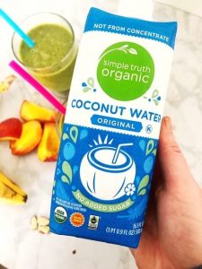 carton of simple truth organic coconut water with green smoothie and peaches in the background