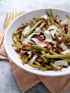 white bowl filled with green beans, shaved parmesan cheese and dried cranberries