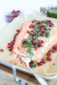 salmon filet topped with pomegranate seeds and herbs