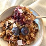 berry crumble in white bowl garnished with fresh blueberries