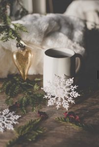 holiday hot beverage in a white mub with heart ornament, white snowflake decorations and fir sprigs