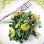 kale, bean and tangerine salad with parsley sage pesto on a white plate with fork