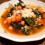 close up of chard, butternut squash, chickpea and bacon soup in white bowl