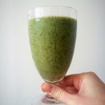 hand holding green smoothie in glass
