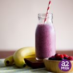 purple berry smoothie in glass bottle with bananas and mixed berries