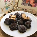 Peanut Butter Banana Dark Chocolate Frozen Truffles on white plate next to framed picture of a couple and a greeting card