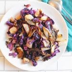 white plate and blue napkin with roasted red cabbage and shallots with hard apple cider glaze