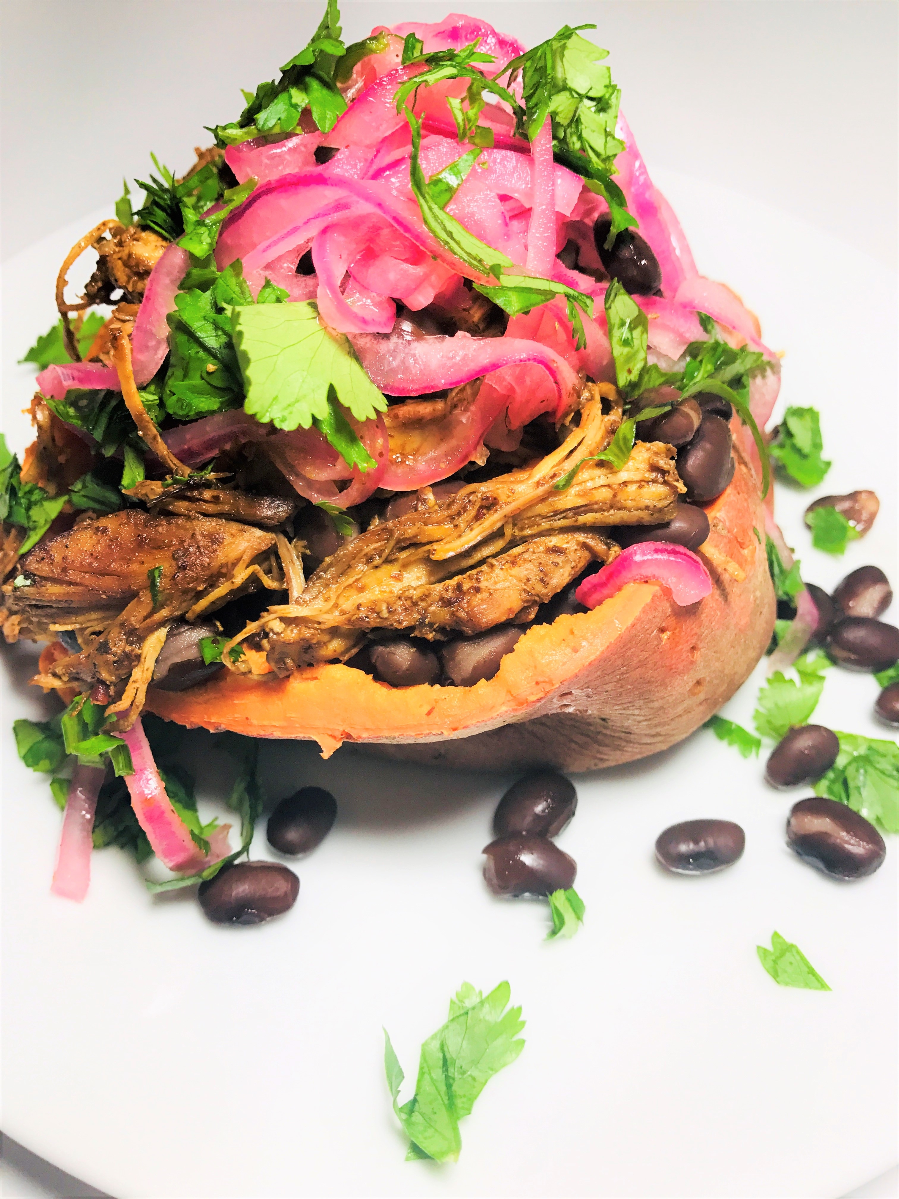 sweet potato stuffed with slow cooker shredded chicken, pickled red onions, cilantro and black beans