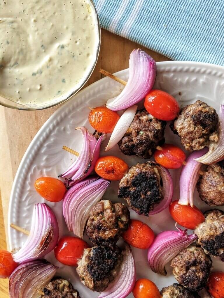 beef kofta meatball kababs with red onion and tomatoes