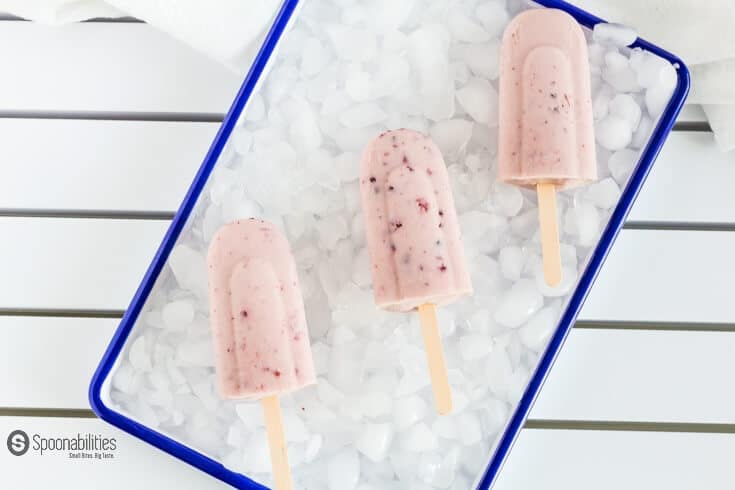 coconut cream and lingonberry popsicles on top of a bed of ice cubes