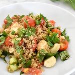 white bowl with quinoa bruschetta salad and basil leaves