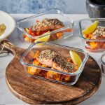 glass meal prep container with za'atar rubbed roasted salmon and slices of roasted sweet potatoes and red peppers