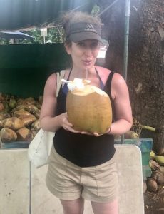 Lindsey Pine trinkt Kokosnusswasser aus einem Strohhalm einer jungen Kokosnuss in Maui
