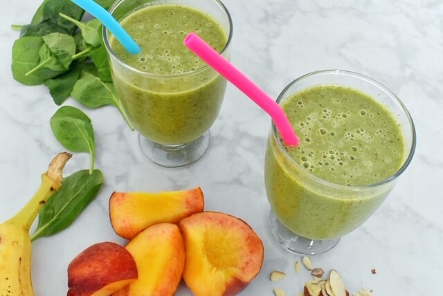 green smoothie with spinach, sliced peaches, banana, and sliced almonds