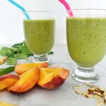 green smoothie with baby spinach, sliced peaches and sliced almonds