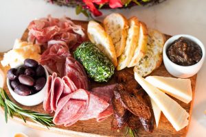 charcuterie board with cheese, salami, sliced bread and olives